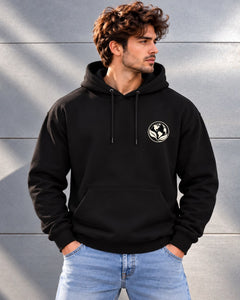 Man wearing the black One Planet hoodie, with a small cream earth-and-leaf emblem on the chest